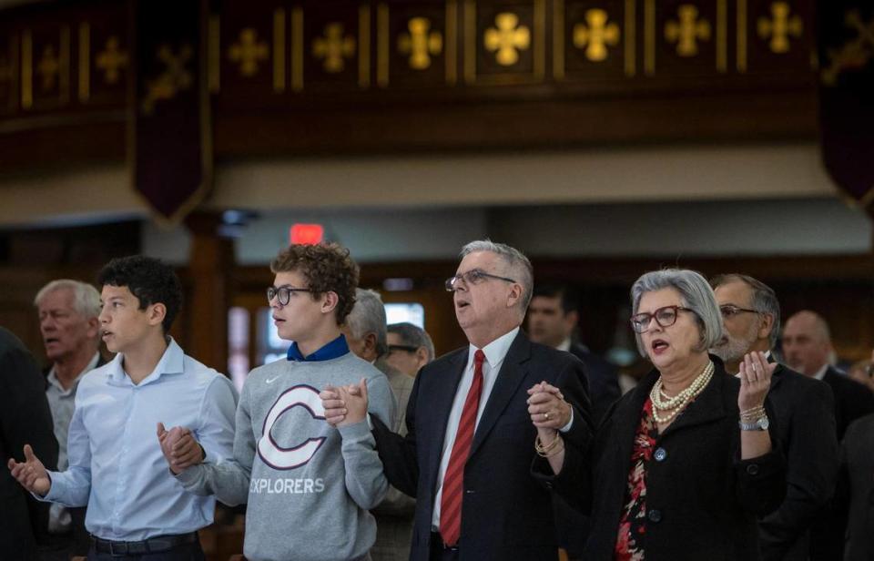 William Castro, second from right, prays with his family, sons Eric and Danny, and his wife Mari Jimenez during a mass at Gesu Catholic Church in downtown Miami on Thursday, Dec. 1, 2022.