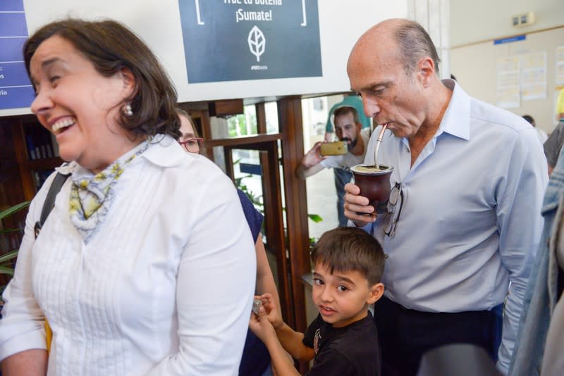 Daniel Martínez, candidato presidencial del partido Frente Amplio, bebe mate mientras espera con su esposa Laura Motta y su nieto Luciano para emitir su voto, en un colegio electoral en Montevideo