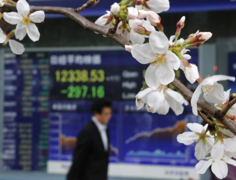 FILE PHOTO - A man walks past an electronic screen displaying the Nikkei share average as cherry blossoms are in full bloom outside a brokerage in Tokyo March 22, 2013. REUTERS/Toru Hanai