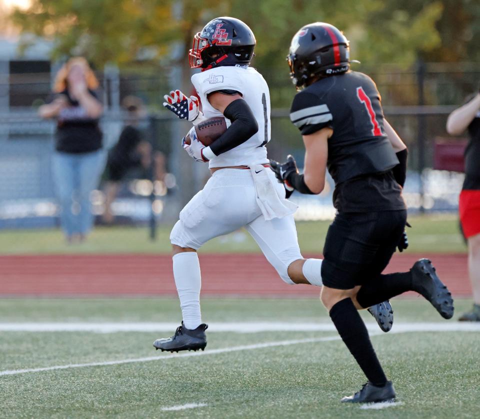 Luther's Ruben Vega, left, runs for a touchdown in front of Crossings defender Mack Gudell during a high school football game at Crossings Christian School in Oklahoma City, Friday, Sept. 22, 2023.