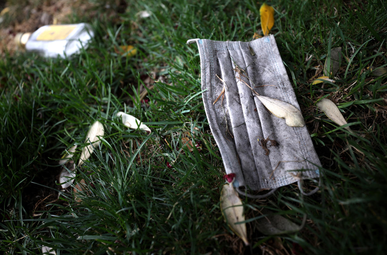 A discarded surgical mask sits on grass