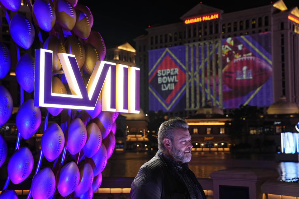 A man stands by signage for the Super Bowl along the Las Vegas Strip ahead of the Super Bowl 58 NFL football game Wednesday, Feb. 7, 2024, in Las Vegas. (AP Photo/John Locher)