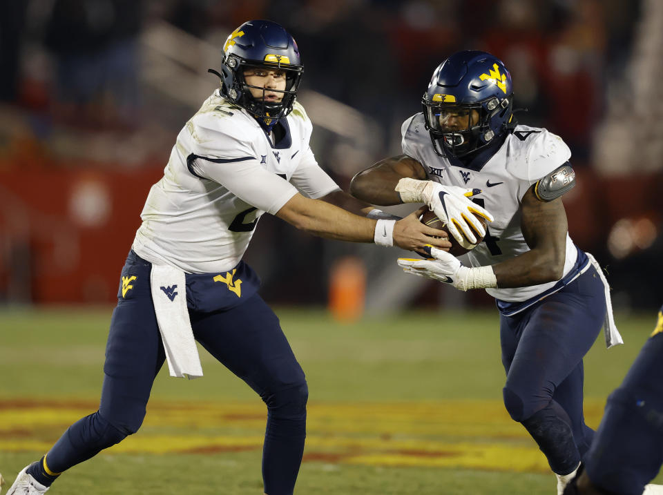 West Virginia quarterback Jarret Doege, left, hands off to running back Leddie Brown during the second half of the team's NCAA college football game against Iowa State, Saturday, Dec. 5, 2020, in Ames, Iowa. (AP Photo/Matthew Putney)