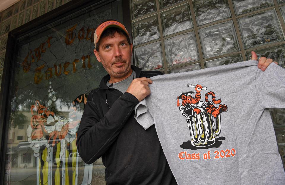 Cameron Farish, co-owner of Tiger Town Tavern in Clemson, shows a T-shirt he made to sell graduates through the Tiger Town Graphics website, since Clemson University's campus is closed from the COVID-19 pandemic.
