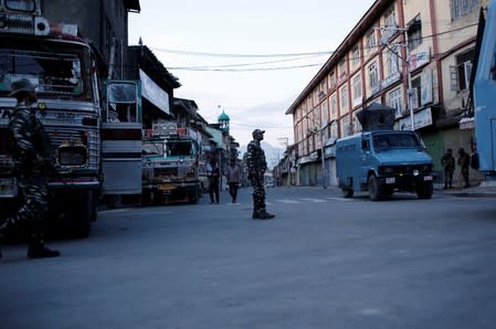 Indian security force personnel stand on a deserted road during restrictions after scrapping of the special constitutional status for Kashmir by the Indian government, in Srinagar