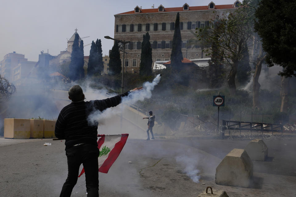 Retired members of the Lebanese security and other protesters return tear gas canisters towards riot police during a protest demanding better pay in Beirut, Lebanon, Wednesday, March 22, 2023. Lebanese security forces fired tear gas to disperse hundreds of protesters who tried to break through the fence leading to the government headquarters in downtown Beirut Wednesday amid widespread anger over the harsh economic conditions in the country. (AP Photo/Hassan Ammar)