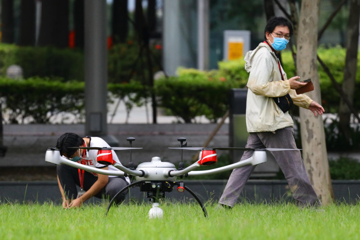 Two men wearing protective mask prepare to fly a drone at Marina Bay on October 24, 2021 in Singapore.  (Photo by Suhaimi Abdullah/NurPhoto via Getty Images)