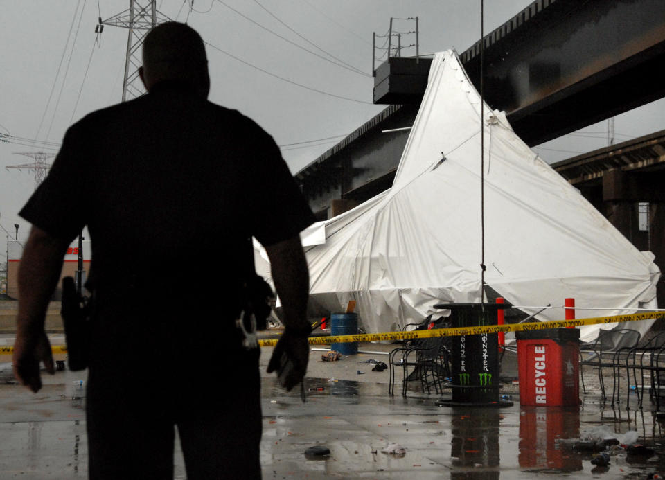 An officer from the Terminal Railroad Police Department surveys a party tent from Kilroy's Sports Bar in St. Louis as it rests against a railroad trestle near the bar after storm winds blew through the area following a baseball game between the St. Louis Cardinals and Milwaukee Brewers at nearby Busch Stadium Saturday, April 28, 2012. One person died Saturday and more than a dozen were taken to a hospital with injuries after high winds blew over a beer tent near Busch Stadium in St. Louis. (AP Photo/Sid Hastings)