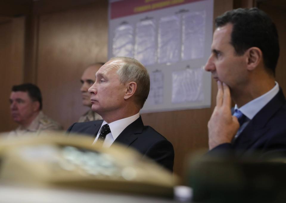 FILE - Russian President Vladimir Putin, center, and Syrian President Bashar Assad, 2nd right, meet with military personnel at the Hemeimeem air base in Syria, on Dec. 11, 2017. The Russian military intervention in Syria allowed Syrian President Bashar Assad's government to reclaim control over most of the country and helped expand Moscow's clout in the Middle East. (Mikhail Klimentyev, Sputnik, Kremlin Pool Photo via AP, File)