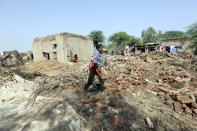 A family collects items from the remains of their home damaged by flooding after heavy rains in the Shikarpur district of Sindh province, Pakistan, Tuesday, Aug. 30, 2022. Disaster officials say nearly a half million people in Pakistan are crowded into camps after losing their homes in widespread flooding caused by unprecedented monsoon rains in recent weeks. (AP Photo/Fareed Khan)