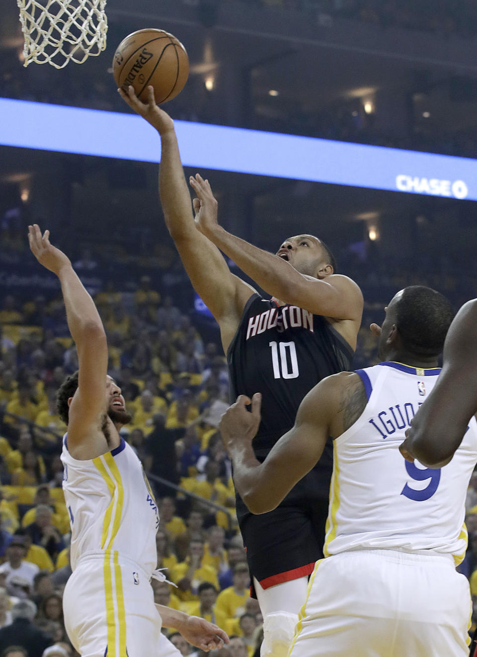 Houston Rockets guard Eric Gordon (10) shoots between Golden State Warriors guards Klay Thompson, left, and Andre Iguodala during the first half of Game 1 of a second-round NBA basketball playoff series in Oakland, Calif., Sunday, April 28, 2019. (AP Photo/Jeff Chiu)