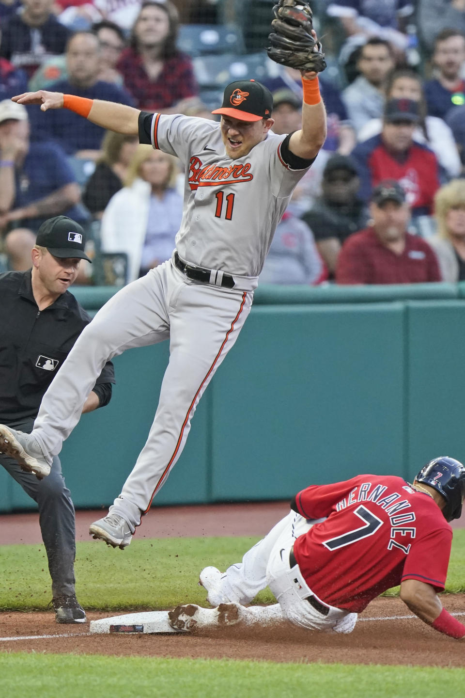 Baltimore Orioles' Pat Valaika (11) jumps for the ball as Cleveland Indians' Cesar Hernandez (7) advances to third base on a wild pitch in the first inning of a baseball game, Monday, June 14, 2021, in Cleveland. (AP Photo/Tony Dejak)