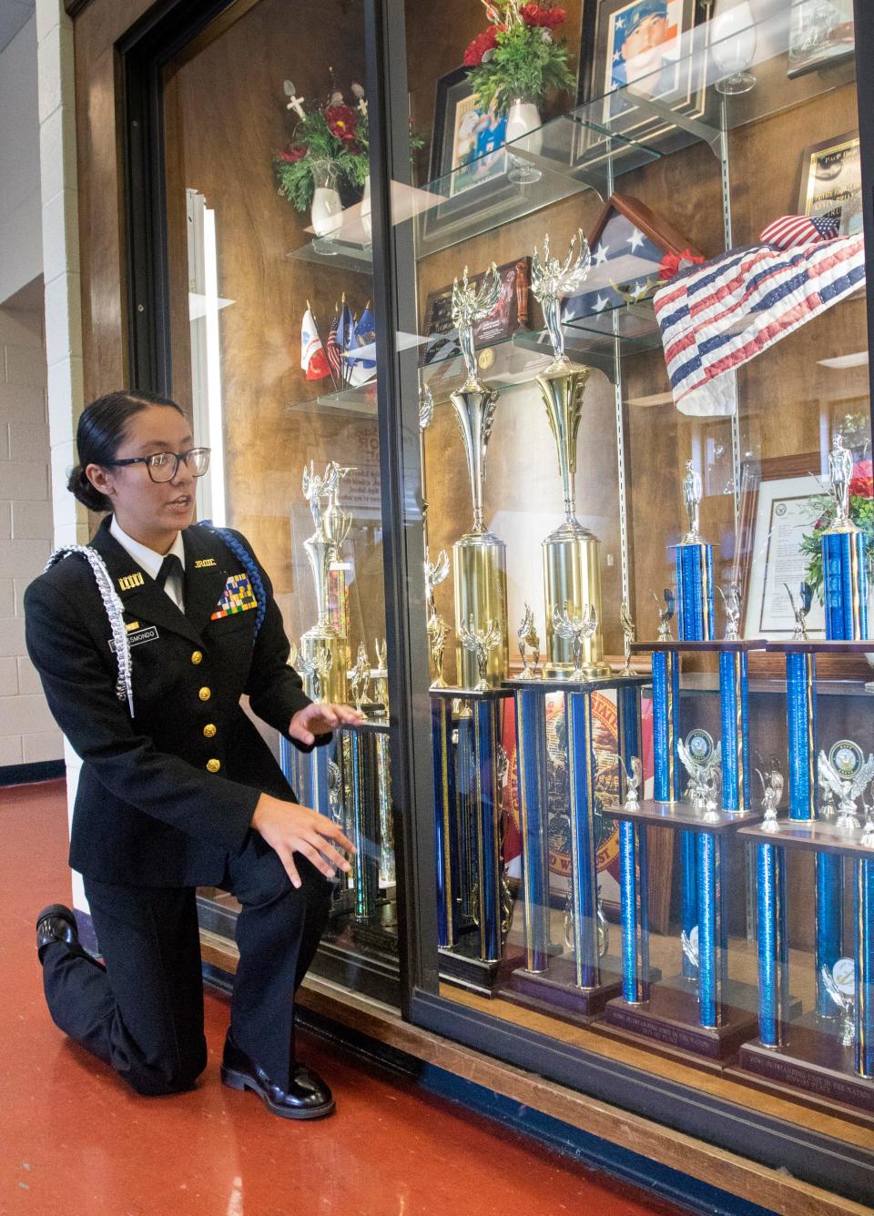 Cadet Commander Sadie Resmondo, 16, points out some of the national Navy JROTC trophies displayed at Pace High School on Friday.