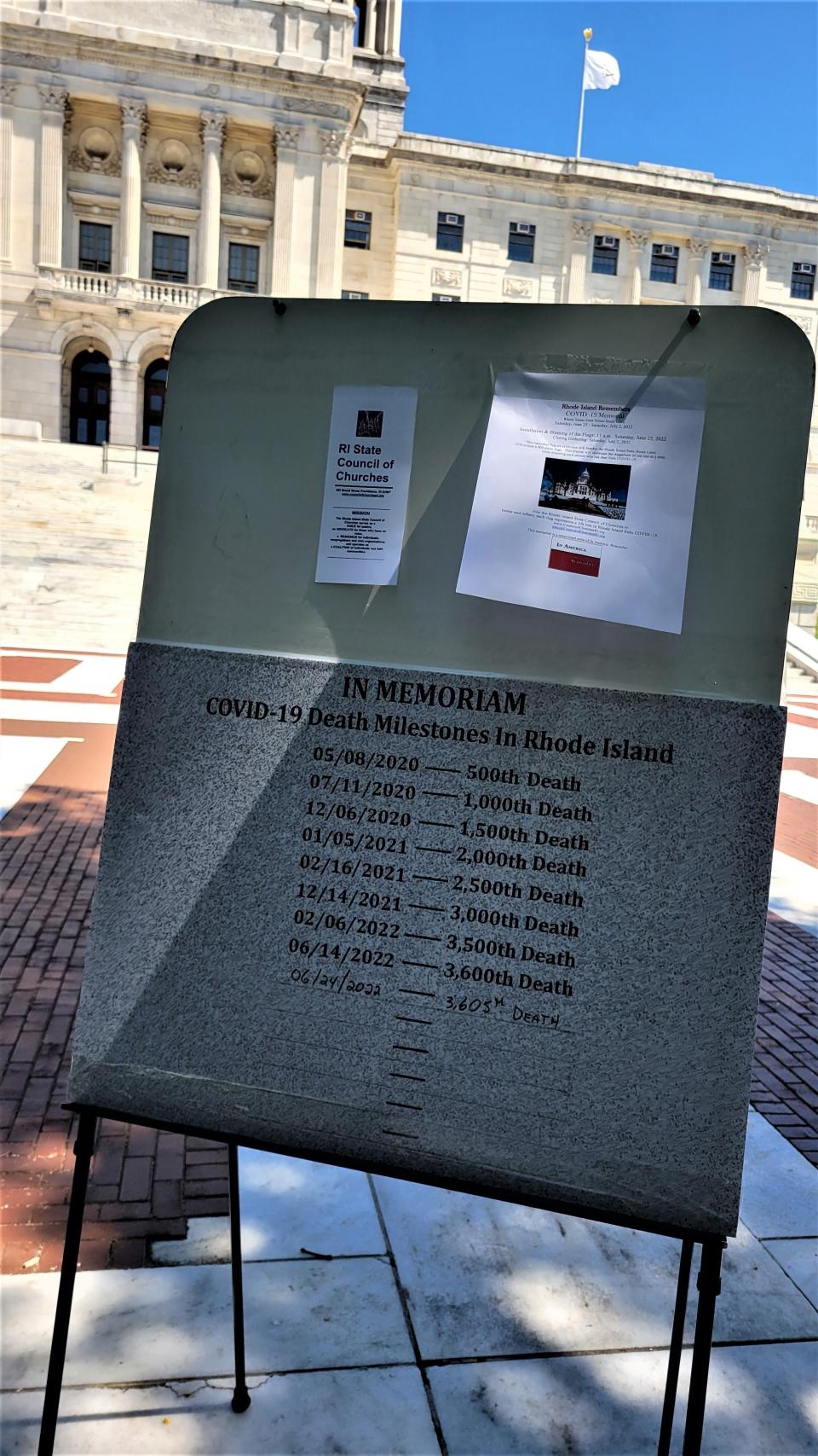 Rhode Island's COVID-19 death milestones are listed on a display on the State House steps.