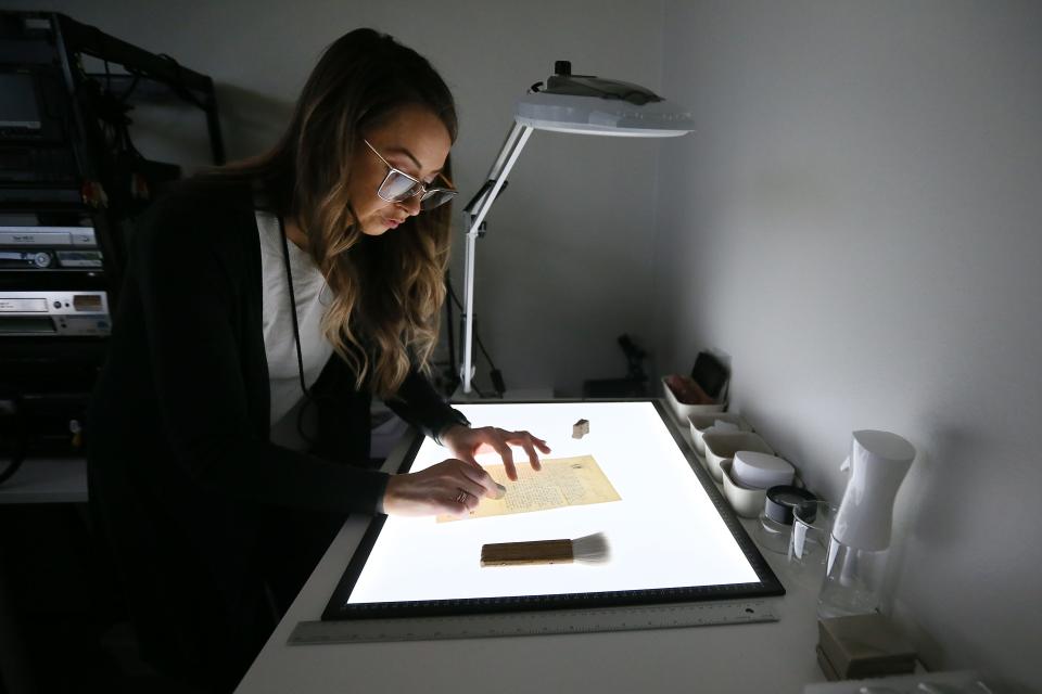 Brooke Lake, archivist and founder of Monocurate, does a dry cleaning treatment before encapsulation while working on a document.