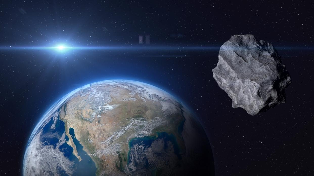  An asteroid floating in space with Earth and the sun in the background. 