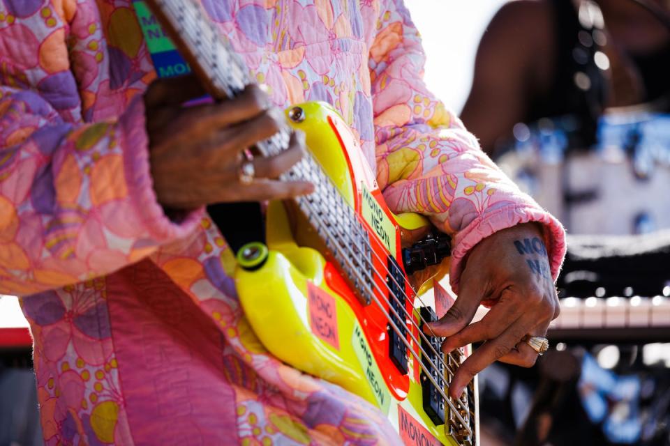 Крупный план музыканта в ярких цветах, играющего на желто-красной бас-гитаре