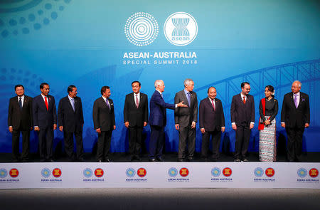 Australia's Prime Minister Malcolm Turnbull gestures to ASEAN leaders Laos' Prime Minister Thongloun Sisoulith, Indonesia's President Joko Widodo, Cambodia's Prime Minister Hun Sen, Brunei's Sultan and Prime Minister Sultan Bokliah, Thailand's Prime Minister Prayut Chan-O-Cha, Singapore's Prime Minister Lee Hsien Loong, Vietnam's Prime Minister Nguyen Xuan Phuc, Philippines' Secretary of Foreign Affairs Alan Peter Cayetano, Myanmar's State Counsellor Aung San Suu Kyi and Malaysia's Prime Minister Najib Razak to leave the stage after posing for the Leaders Welcome and Family Photo at the one-off summit of 10-member Association of Southeast Asian Nations (ASEAN) in Sydney, Australia, March 17, 2018. REUTERS/David Gray