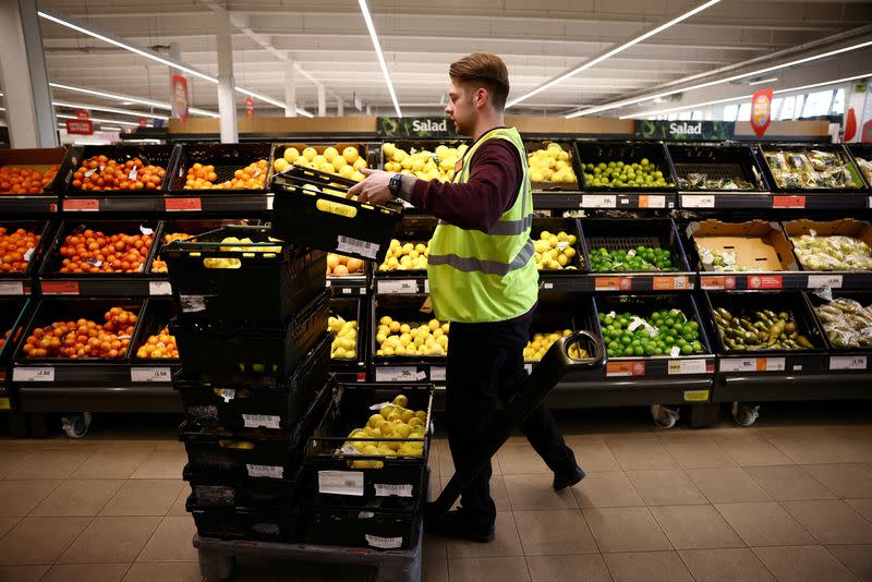 FILE PHOTO: An employee arranges produce inside a Sainsbury’s supermarket in Richmond, west London