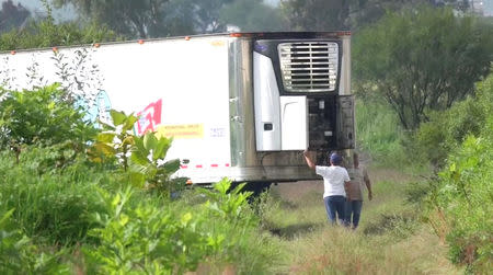 Men stand by an abandoned trailer full of bodies that has been parked in Tlajomulco de Zuniga, Jalisco, Mexico September 15, 2018 in this still image taken from a video obtained September 17, 2018. REUTERS TV/via REUTERS