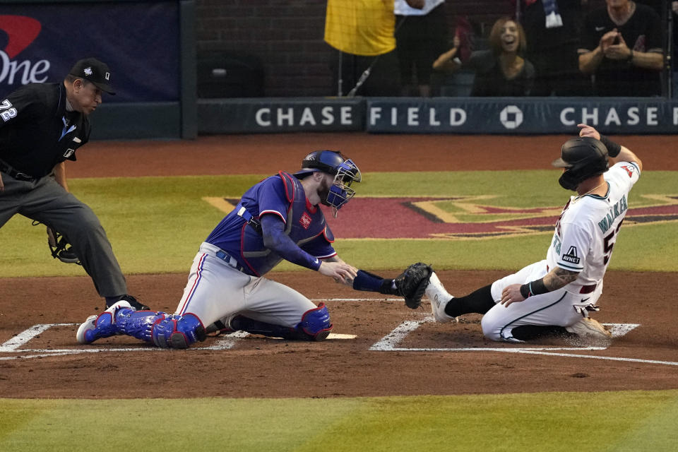 Arizona Diamondbacks' Christian Walker, right, is tagged out by Texas Rangers catcher Jonah Heim at home plate during the second inning in Game 3 of the baseball World Series Monday, Oct. 30, 2023, in Phoenix. (AP Photo/Ross D. Franklin)