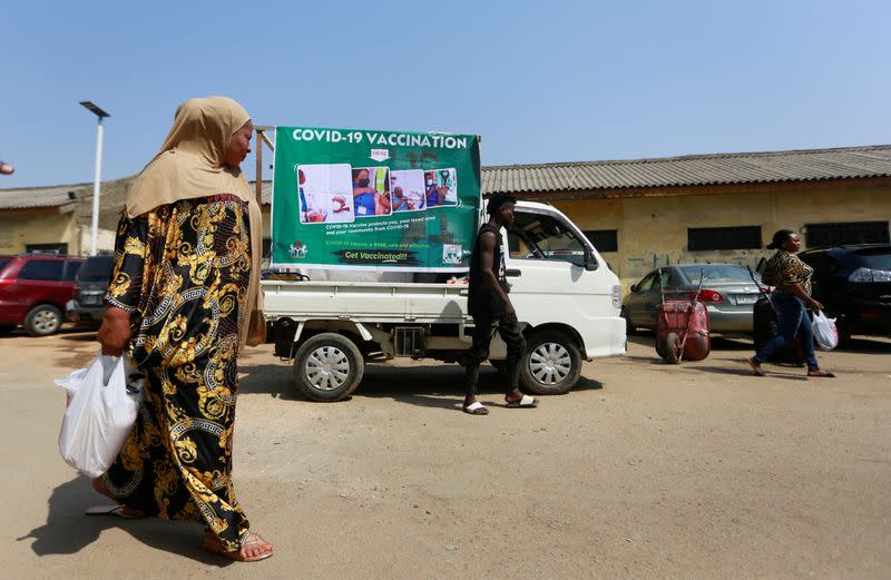 Woman walks past a COVID-19 campaign truck during a mass vaccination exercise in Abuja