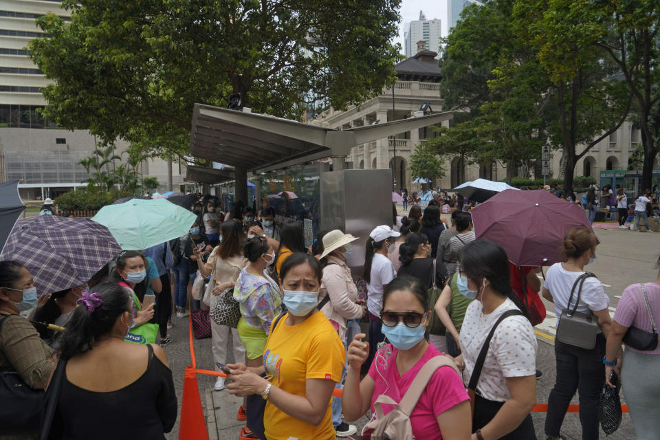 In this Saturday, May 1, 2021, photo, domestic helpers from the Philippines line up at the temporary testing center for COVID-19, in Hong Kong. Hong Kong officials have dropped a plan to make it mandatory for foreign domestic workers to be vaccinated against the coronavirus, after the move drew criticism that it was discriminatory. (AP Photo/Kin Cheung)