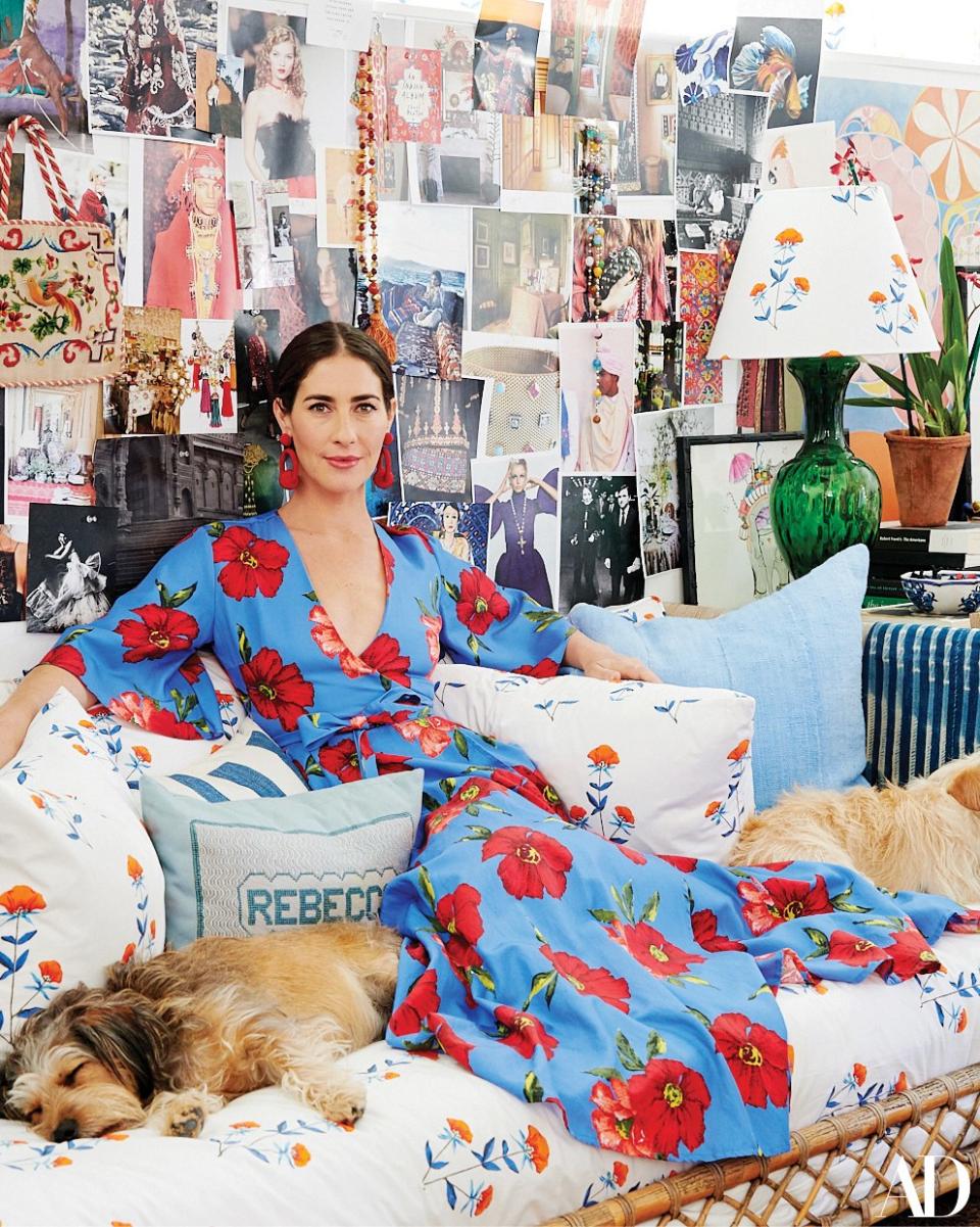 Rebecca de Ravenel, in a dress and earrings from her namesake line, at home in Los Angeles with her dogs, Frida and Luna; the Serena & Lily daybed is clad in her poppy print, and the needlepoint pillow was made by her grandmother.
