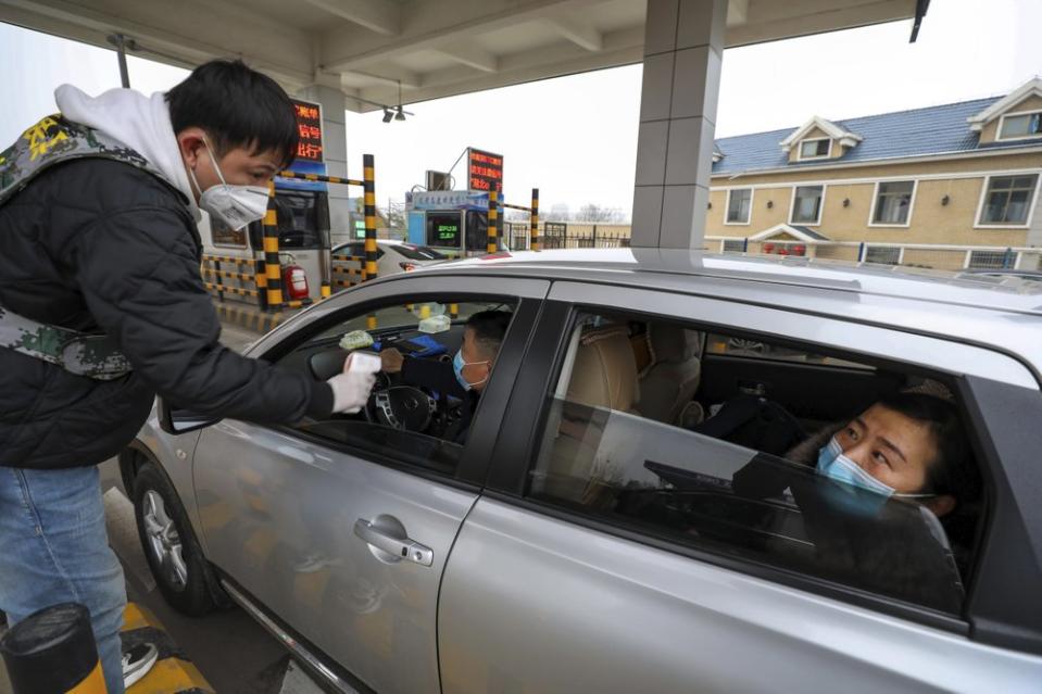 A militia member uses a thermometer gun to take a driver's temperature at a Wuhan toll gate amid the coronavirus outbreak.