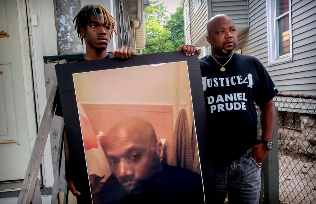 Armin Prude (left) and Joe Prude hold an enlarged photo of Daniel Prude, on Sept. 3, 2020. City officials in Rochester, New York, have agreed to pay $12 million to the family of Prude, a Black man who died after police held him down until he stopped breathing after encountering him running naked through the snowy streets of Rochester. A federal judge approved the settlement in a court document filed Thursday, Oct. 6, 2022. (AP Photo/Ted Shaffrey, File)