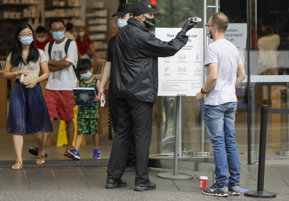 A security guard takes the temperature of a customer at a shopping precinct in Sydney. Source: AAP