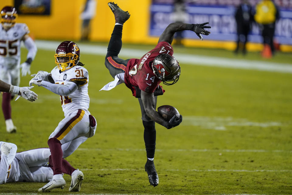 Tampa Bay Buccaneers wide receiver Chris Godwin (14) leaps over Washington Football Team strong safety Kamren Curl (31) during the second half of an NFL wild-card playoff football game, Saturday, Jan. 9, 2021, in Landover, Md. Tampa Bay won 31-23. (AP Photo/Al Drago)
