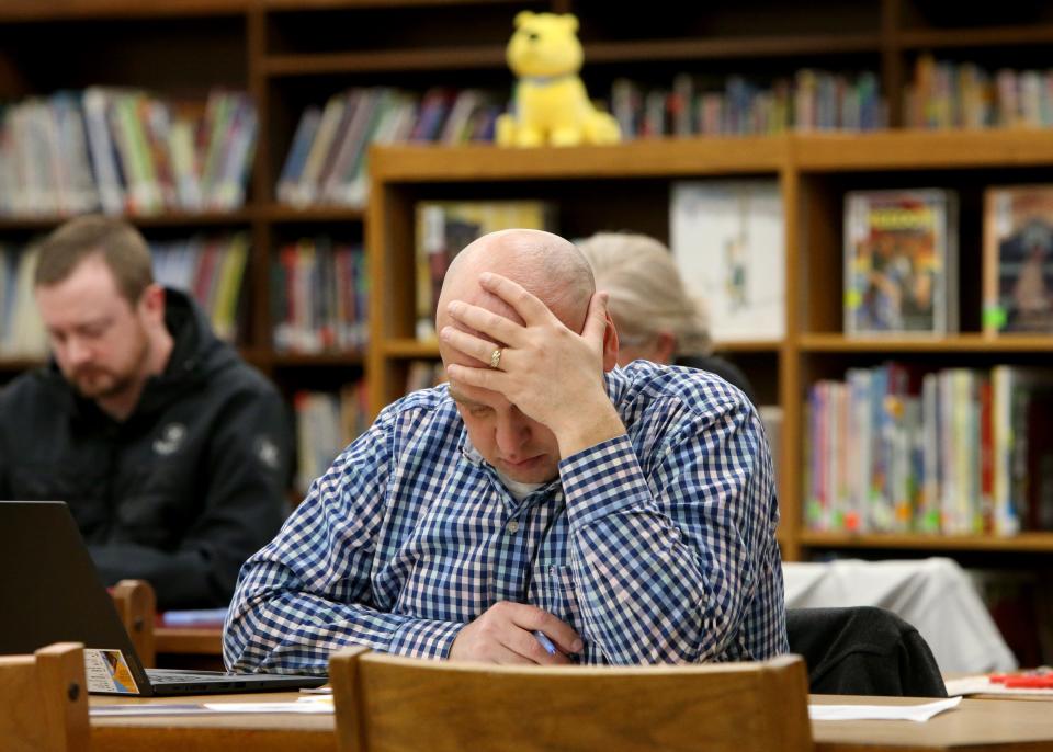 A man looks down at the packet of information  Wednesday, Feb. 8, 2023, at the information session for the South Bend school district’s long-range facilities master plan at Clay International Academy in South Bend.
