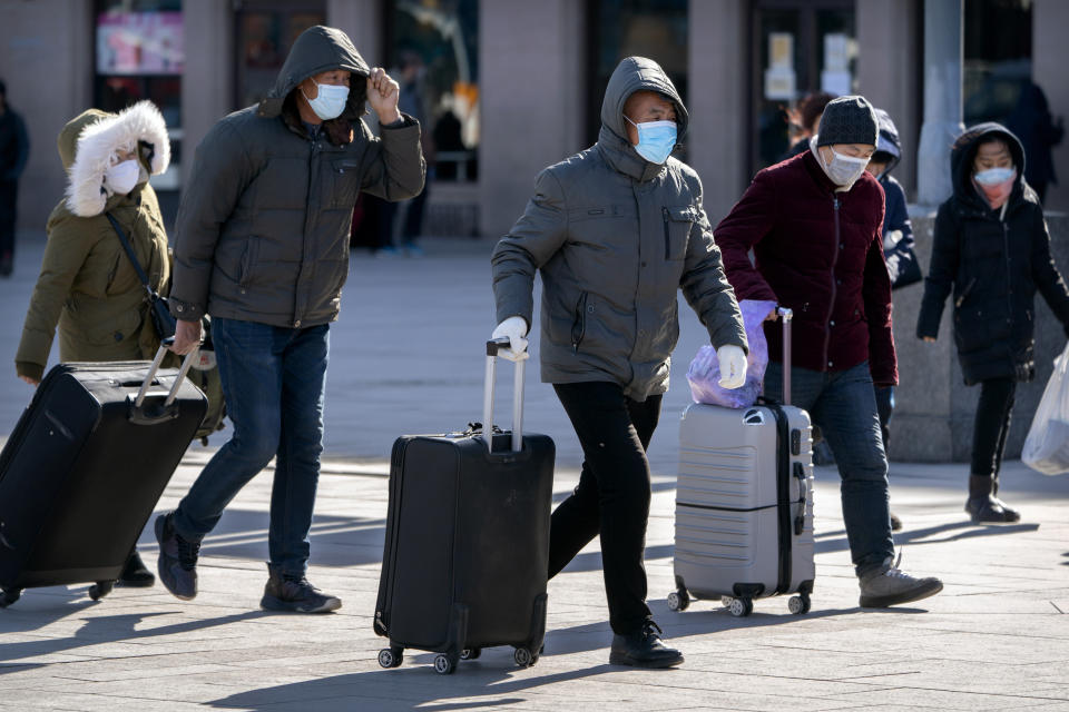 Travelers wearing face masks to protect against the spread of the coronavirus walk with their luggage at the Beijing Railway Station in Beijing, Thursday, Jan. 28, 2021. Efforts to dissuade Chinese from traveling for Lunar New Year appeared to be working. Beijing's main train station was largely quiet on the first day of the travel rush and estimates of passenger totals were smaller than in past years. (AP Photo/Mark Schiefelbein)