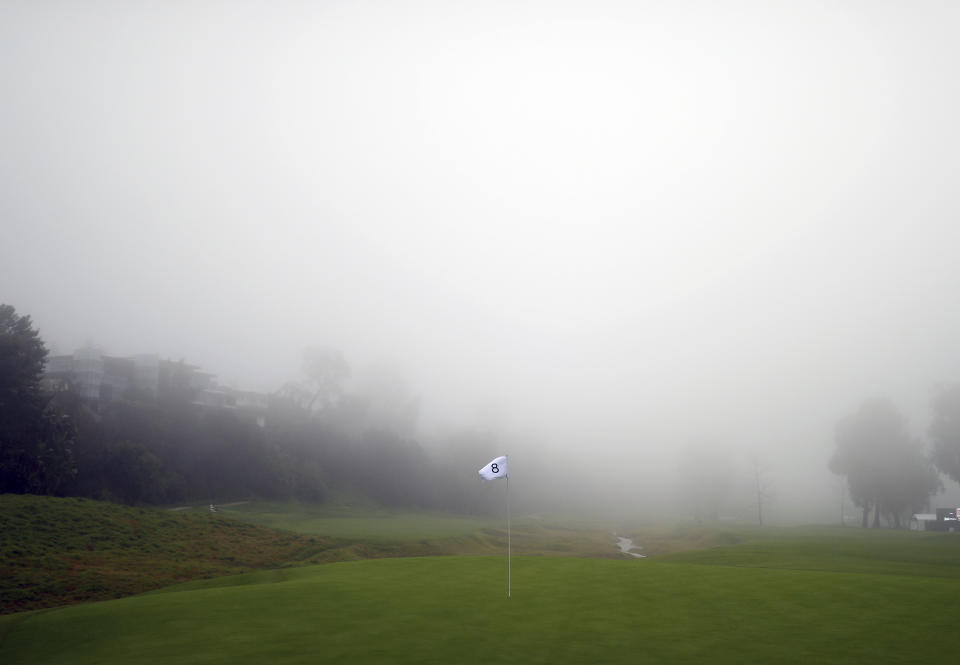 Rain and fog roll onto the golf course seen from the eighth green as play was suspended during the first round of the Genesis Open golf tournament at Riviera Country Club Thursday, Feb. 14, 2019, in the Pacific Palisades area of Los Angeles. (AP Photo/Ryan Kang)