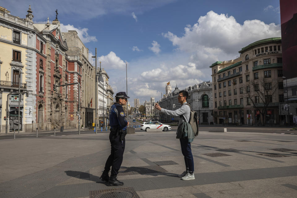 A tourist shows the location of his hotel to a local police in downtown Madrid, Spain, Sunday, March 15, 2020. Spain awoke to its first day of a nationwide quarantine on Sunday after the government declared a two-week state of emergency. The government imposed the special measures including the confinement of people to their homes unless shopping for food and medicine, going to and from work, and to meet other basic needs. The vast majority of people recover from the new coronavirus. According to the World Health Organization, most people recover in about two to six weeks, depending on the severity of the illness. (AP Photo/Bernat Armangue)