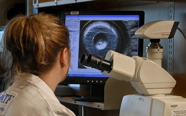 A technician examines the back of a shell casing so the data from it can be entered into the National Integrated Ballistic Information Network, also known as NIBIN.