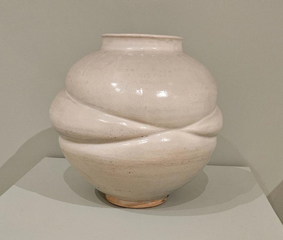 A white porcelain moon jar with indentations left by rope wrapped around it.