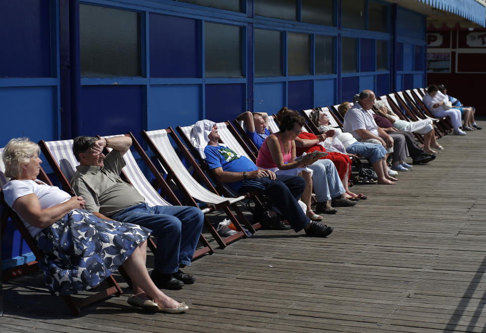 People sit in the sun on deck chairs at Central Pier in Blackpool, northern England July 24, 2013. British beach resorts, which flourished in the 19th century and earlier, have tempted tourists for years with amusement arcades, fairground rides and cheap and cheerful souvenirs. However, as a 2013 report by the Centre for Social Justice states, many seaside towns suffered as from the 1970s it became cheaper and easier for British tourists to travel abroad. Now, according to the Office for National Statistics, larger seaside towns in England suffer from higher-than-average levels of deprivation compared to the rest of the country. Nevertheless, they do continue to attract holiday makers. Picture taken July 24, 2013. REUTERS/Phil Noble (BRITAIN - Tags: SOCIETY TRAVEL)