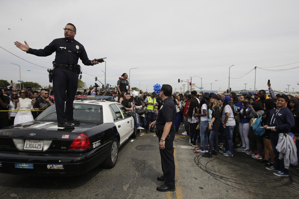 Los Angeles police officers tell the crowd to back up to clear the way for a hearse carrying the casket of slain rapper Nipsey Hussle Thursday, April 11, 2019, in Los Angeles. The 25-mile procession traveled through the streets of South Los Angeles after a memorial service, including a trip past Hussle's clothing store, The Marathon, where he was gunned down March 31. (AP Photo/Jae C. Hong)