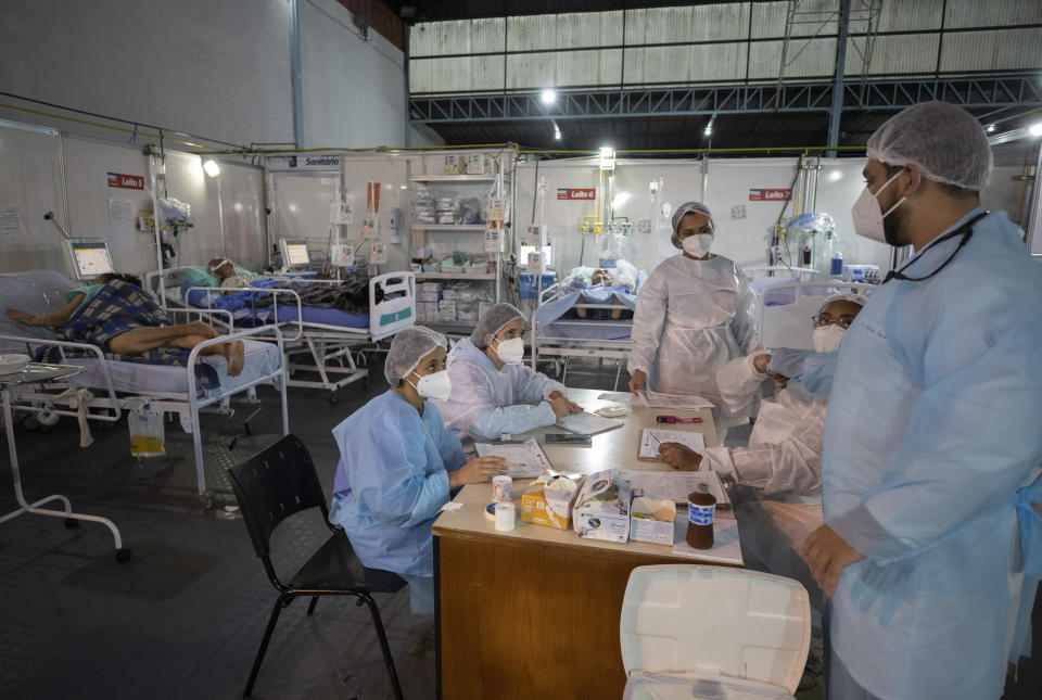 Health workers talk in the emergency unit of a field hospital set up to treat COVID-19 patients in Ribeirao Pires, greater Sao Paulo area, Brazil, Tuesday, April 13, 2021. (AP Photo/Andre Penner)