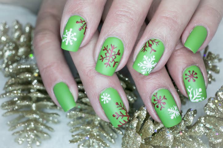 seasonal inspired nail art with bright green base coat and red and white snowflakes painted on