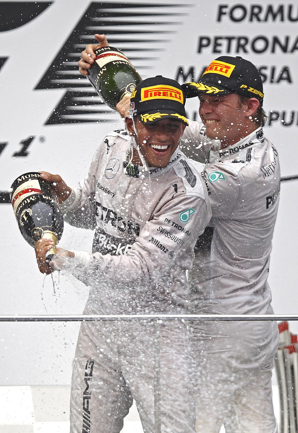 Mercedes driver Lewis Hamilton, left, of Britain and his teammate Nico Rosberg of Germany spray champagnes during the prize presentation on the podium after the Malaysian Formula One Grand Prix at Sepang International Circuit in Sepang, Malaysia, Sunday, March 30, 2014. Hamilton won the race while Rosberg finished in second. (AP Photo/Lai Seng Sin)