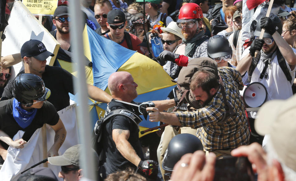 FILE - In this Aug. 12, 2017 file photo, white nationalist demonstrators clash with counter demonstrators at the entrance to Lee Park in Charlottesville, Va. Federal charges against three alleged members of a violent white supremacist group accused of inciting violence at California political rallies were dismissed Monday, June 3, 2019, by Judge Cormac J. Carney in U.S. District Court in Los Angeles, who found their actions amounted to constitutionally protected free speech. (AP Photo/Steve Helber, File)