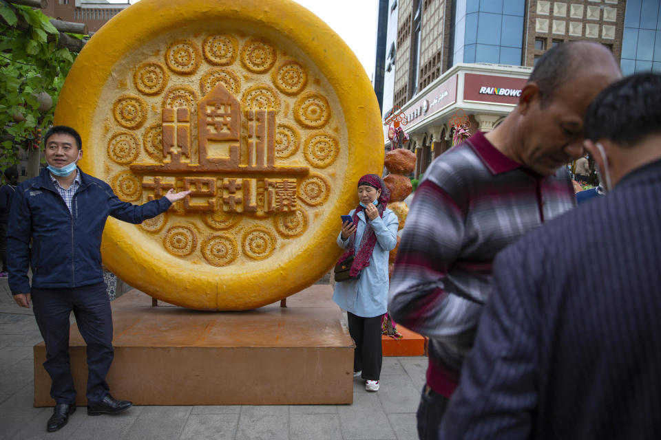Visitors pose for photos with a giant plastic sculpture of a piece of Uyghur's naan bread at the International Grand Bazaar in Urumqi in northwestern China's Xinjiang Uyghur Autonomous Region, during a government organized visit, on April 22, 2021. Four years after Beijing's brutal crackdown on largely Muslim minorities native to Xinjiang, Chinese authorities are dialing back the region's high-tech police state and stepping up tourism. But even as a sense of normality returns, fear remains, hidden but pervasive. (AP Photo/Mark Schiefelbein)
