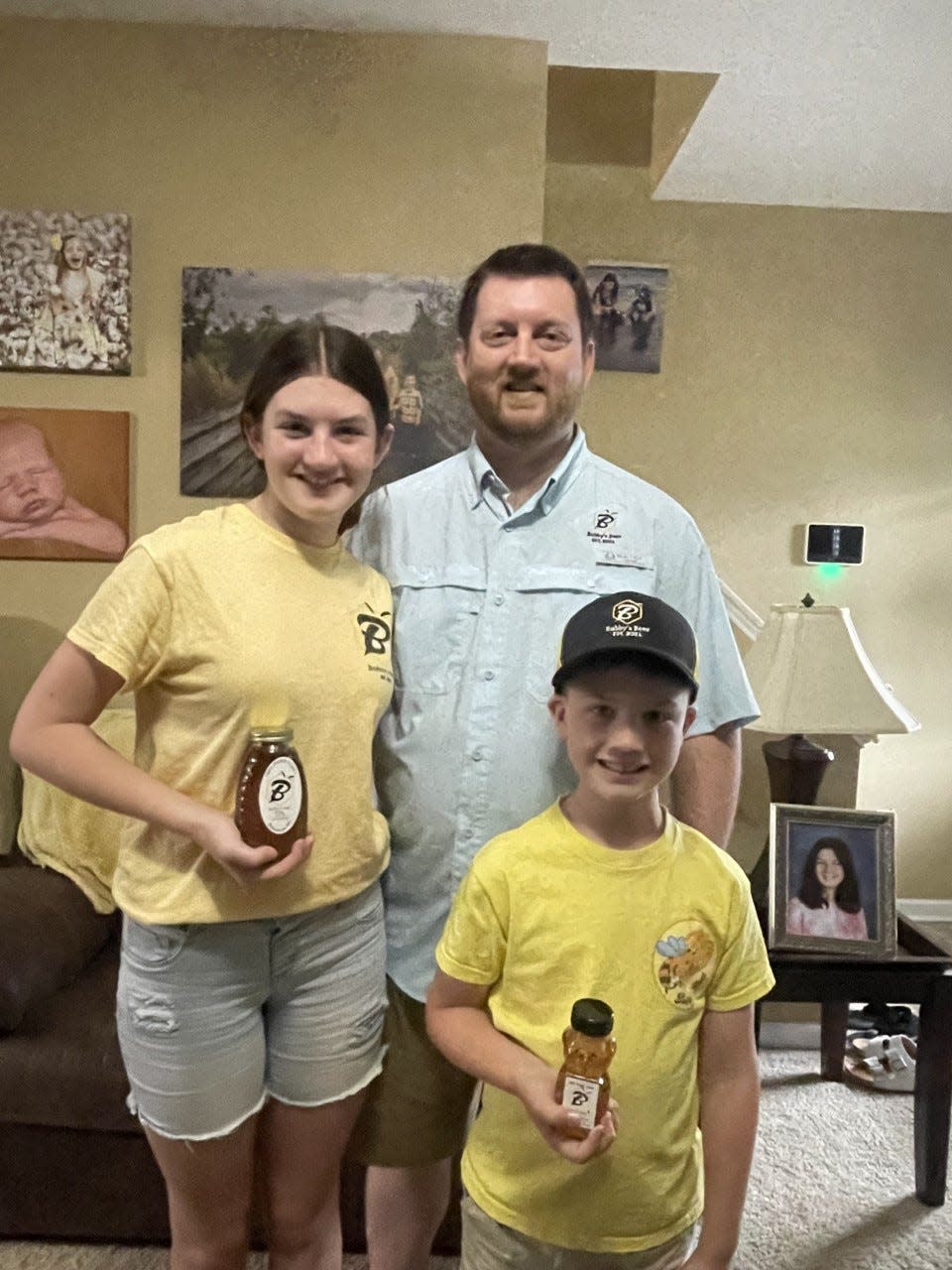 Taylor (left), Carter (front) and dad Randall (right) Jones smile in their Bubby's Bees merchandise. The Richlands family recently began the start-up company.