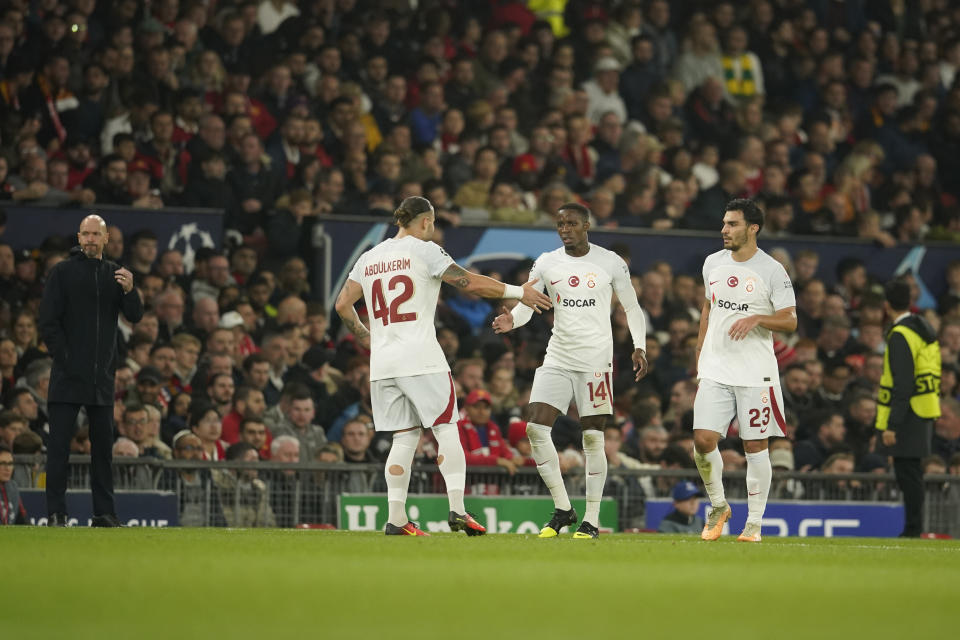 Galatasaray's Wilfried Zaha, second from right, celebrates with his teammates after scoring his side's opening goal as Manchester United's head coach Erik ten Hag, left, reacts during the Champions League group A soccer match between Manchester United and Galatasaray at the Old Trafford stadium in Manchester, England, Tuesday, Oct. 3, 2023. (AP Photo/Dave Thompson)