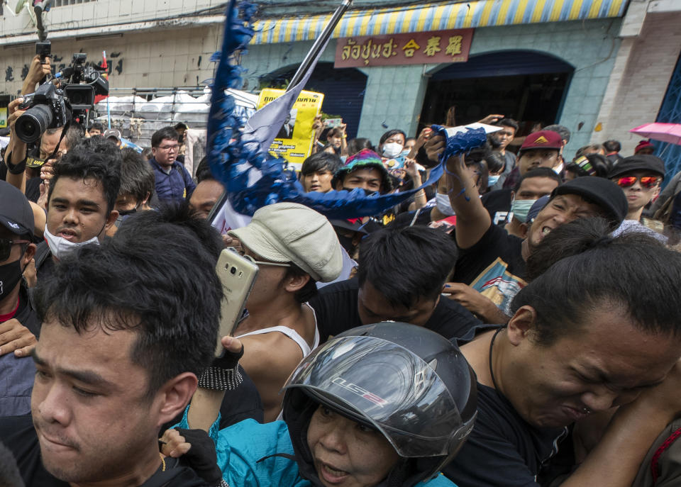 An anti-government protester hurls blue paint to policemen as they arrive at the Samranrat police station in Bangkok, Thailand, Friday, Aug, 26, 2020. The protesters tussled with police in the Thai capital on Friday as 15 of their movement leaders turned up at a police station to answer a summons linked to demonstrations denouncing the arrests. (AP Photo/Sakchai Lalit)