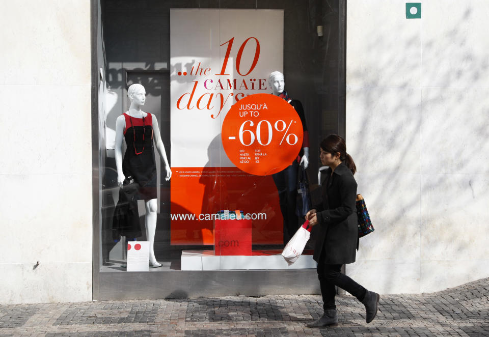 In this picture taken on Friday, March 16, 2012, a woman walks past a shop advertising price reduction on clothes downtown Prague, Czech Republic. The cold winter is over and spring has arrived in Prague, Belgrade and Bucharest but from the look in shop windows, with massive reductions and bargains galore, the winter sales are still on. (AP Photo/Petr David Josek)