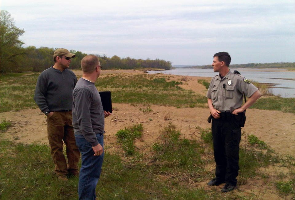 In this Friday, April 13, 2012, photo Ryder Will, left, Wisconsin Department of Natural Resources, DNR Property Manager Brian Hefty and DNR Warden Supervisor Jeremy Plautz, right, discuss closing off the woods surrounding a nude beach in the Town of Mazomanie, Wis. State park officials are planning to close off vast portions of the forest surrounding the famous beach in hopes of curtailing illicit sex. (AP Photo/Todd Richmond)